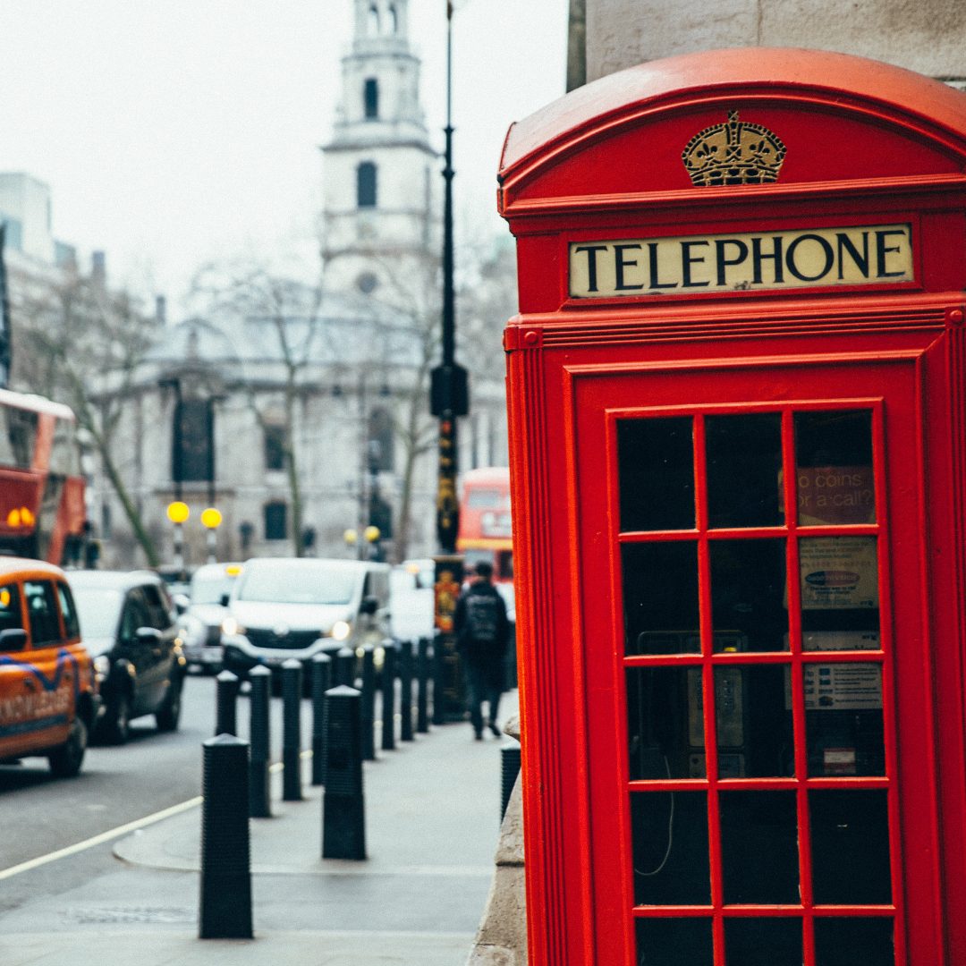 Eine rote Telefonzelle steht am Straßenrand in London.