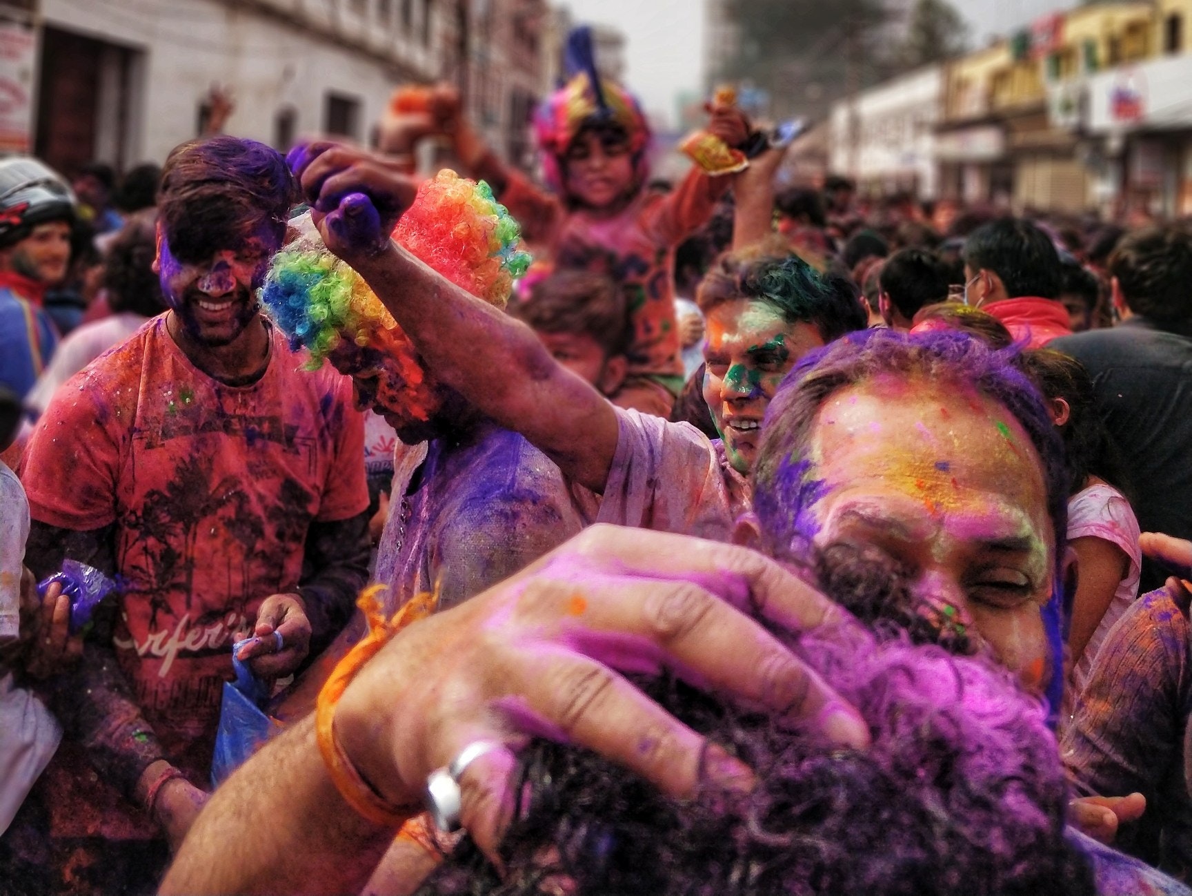 Eine große Gruppe von Menschen ist mit bunten Farben bedeckt und umarmt sich.
