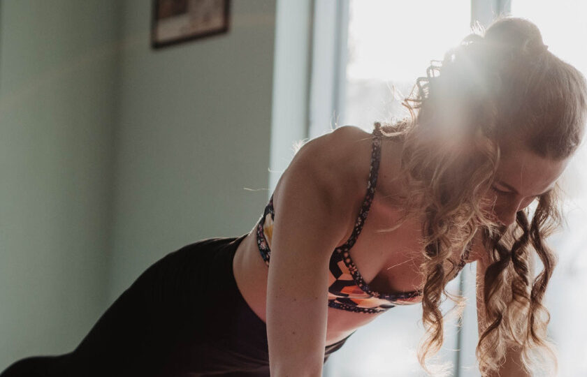 Frau in schwarzem Tanktop und schwarzen Leggings beim Yoga