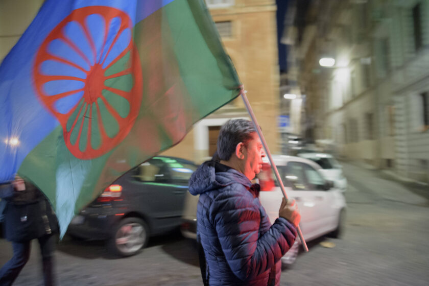 Ein Mann trägt die internationale Flagge des Roma-Volkes