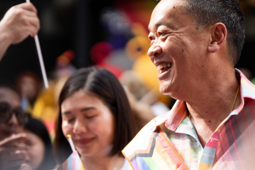 Thailands Premierminister Srettha Thavisin nimmt an einer Pride-Parade in Bangkok teil. Er trägt eine Regenbogenschärpe und die Menschen um ihn herum halten Regenbogenfahnen hoch.