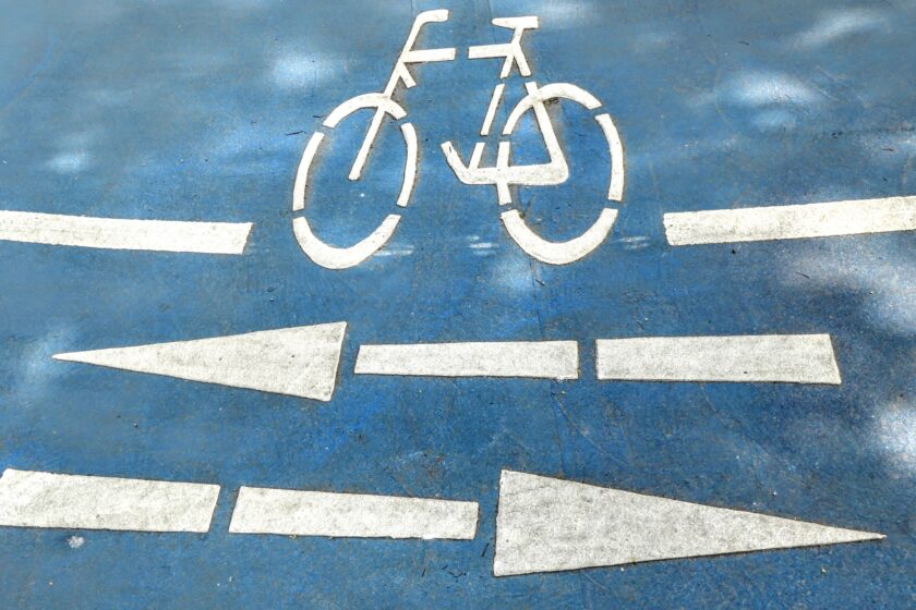 Verkehrsmarkierungen auf einer Straße zeigen ein Fahrrad und Pfeile sowohl nach links als auch nach rechts