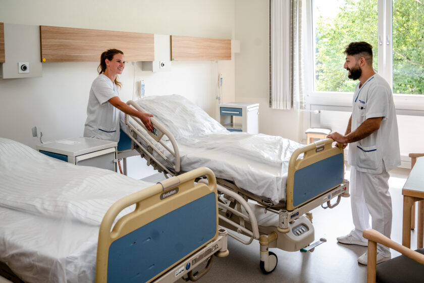 zwei Pflegefachkräfte richten ein Krankenhausbett her