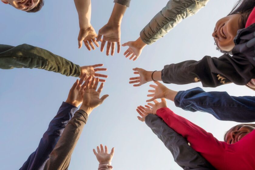 Menschen stehen im Kreis und halten ihre Hände zusammen