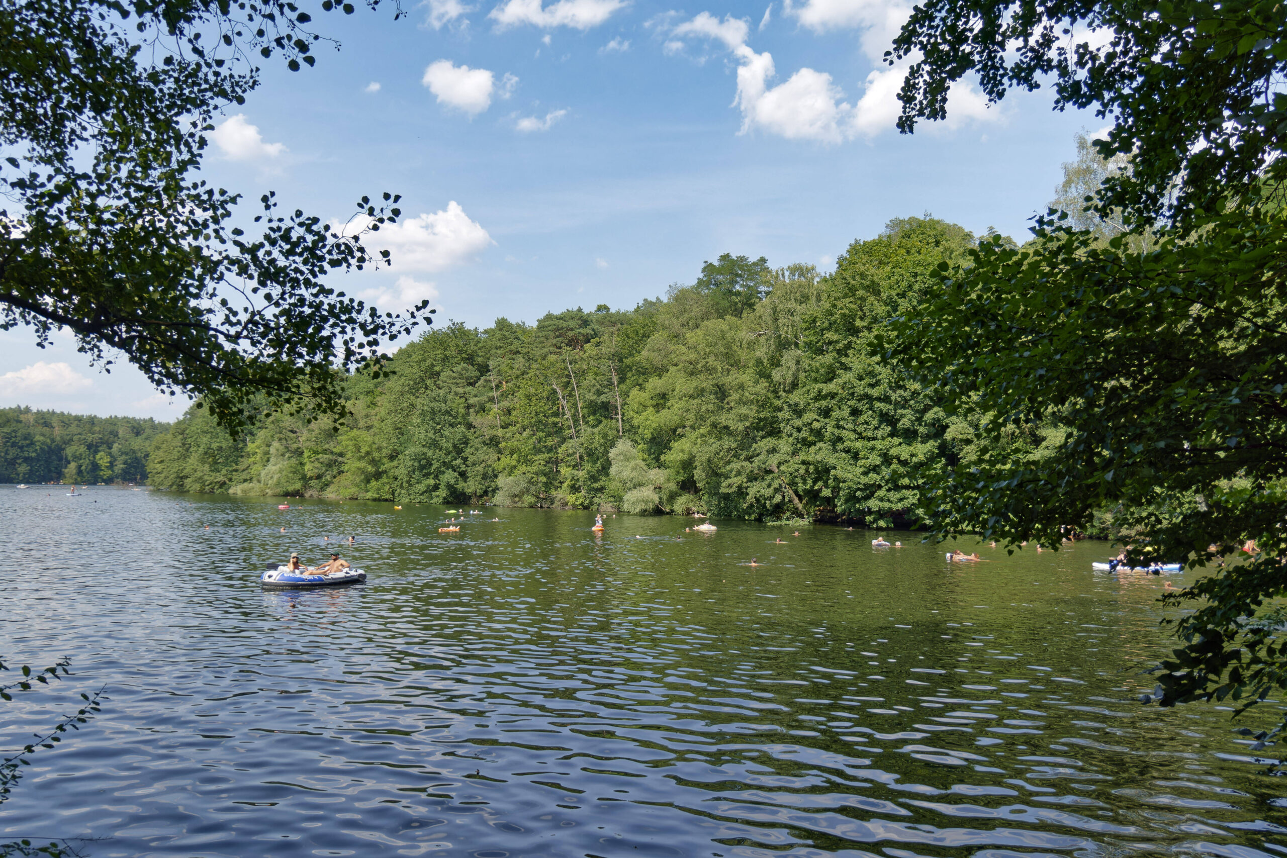 viel los auf der Krummen Lanke (einem See) bei Berlin: Mehrere Menschen sind bei Sommerwetter in Booten und Stand-up Paddeln auf dem See unterwegs