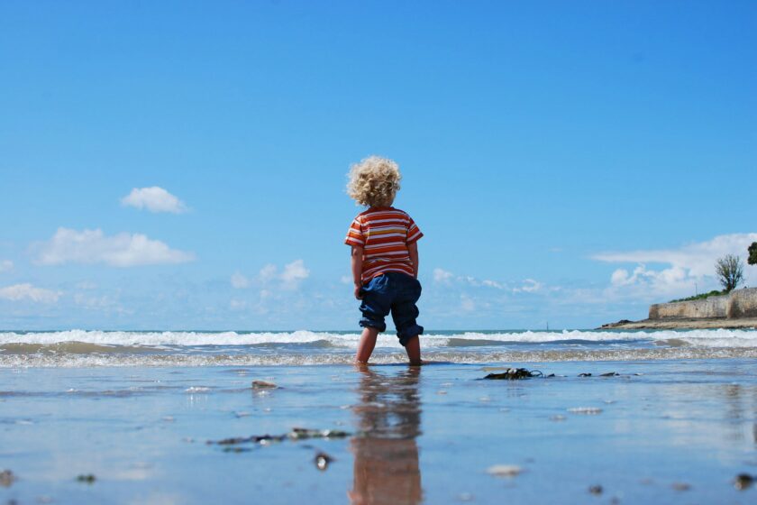 ein Kind steht im Wasser am Strand