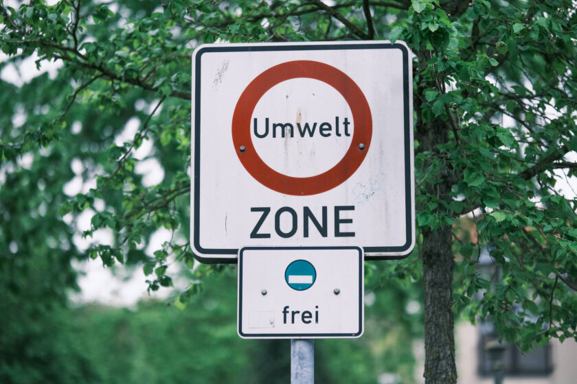 Ein Verkehrsschild mit dem Begriff "Umweltzone", im Hintergrund grün belaubte Bäume