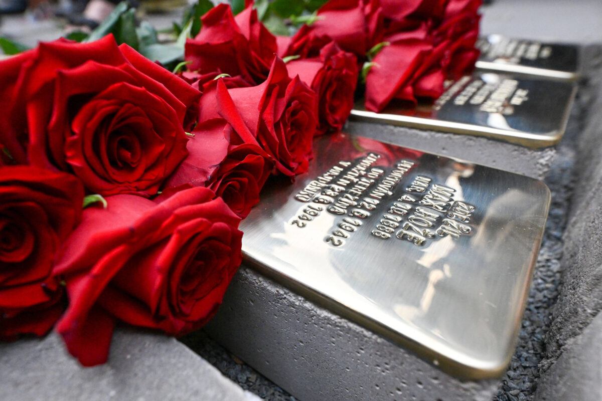 Eine Reihe frisch gesetzter Stolpersteine in Brno, Tschechien. Auf ihnen liegt ein Strauß roter Rosen.