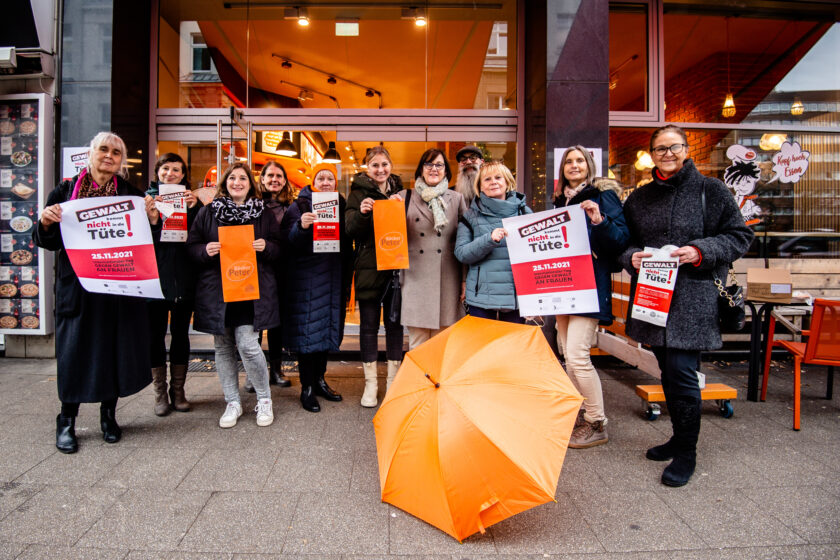 Menschen stehen vor der Bäckerei Peter in Essen. Sie halten Poster und Bäckereitüten, auf denen "Gewalt kommt nicht in die Tüte". Dies ist eine Aktion anlässlich des heutigen (25.11.2024) Internationalen Tages Tag gegen Gewalt an Frauen und Mädchen.