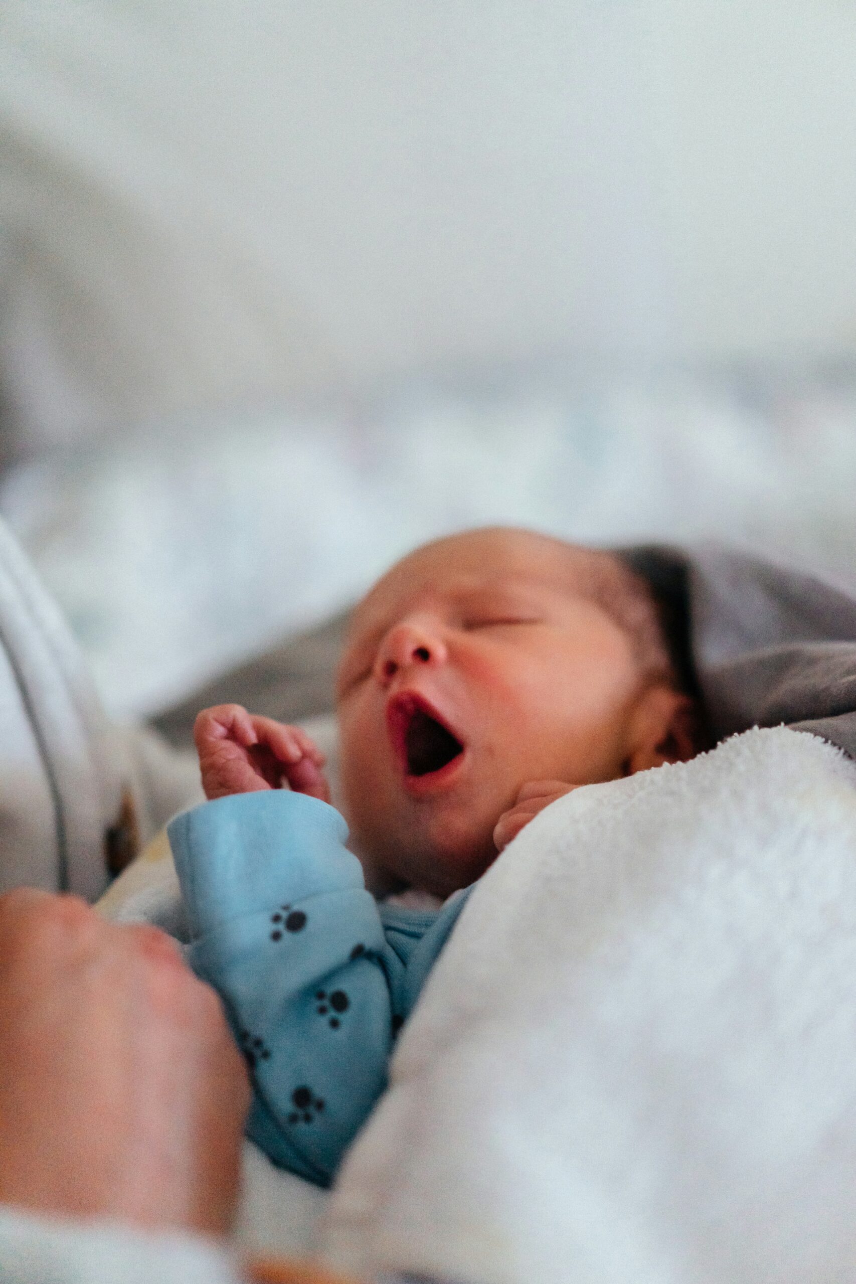 ein kleines, in mehrere Decken gewickeltes gähnendes Baby