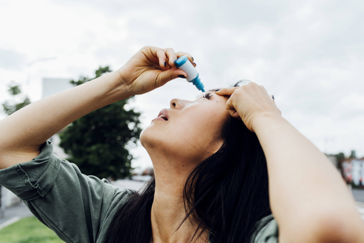 Young woman putting drop in eye