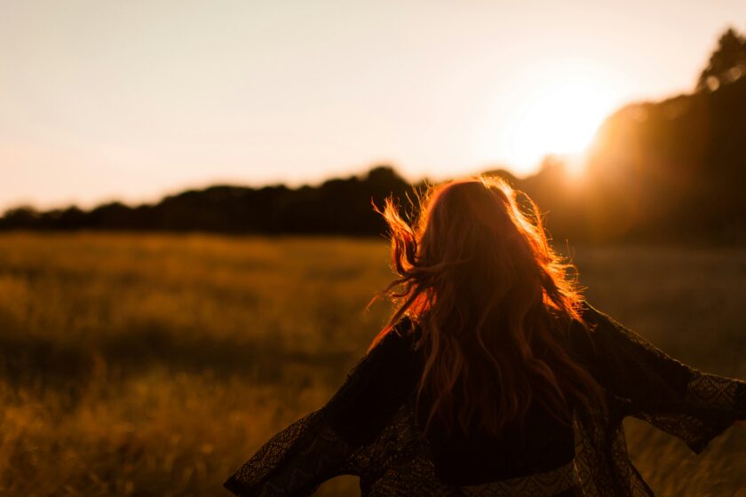 Frau läuft bei Sonnenuntergang über eine Wiese
