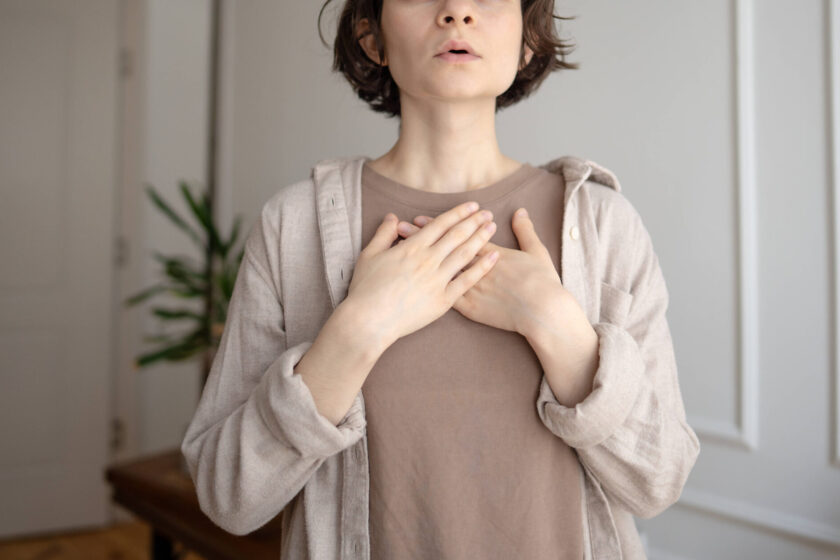 Junge Frau praktiziert Stressabbau, macht Atemübungen zur Beruhigung,