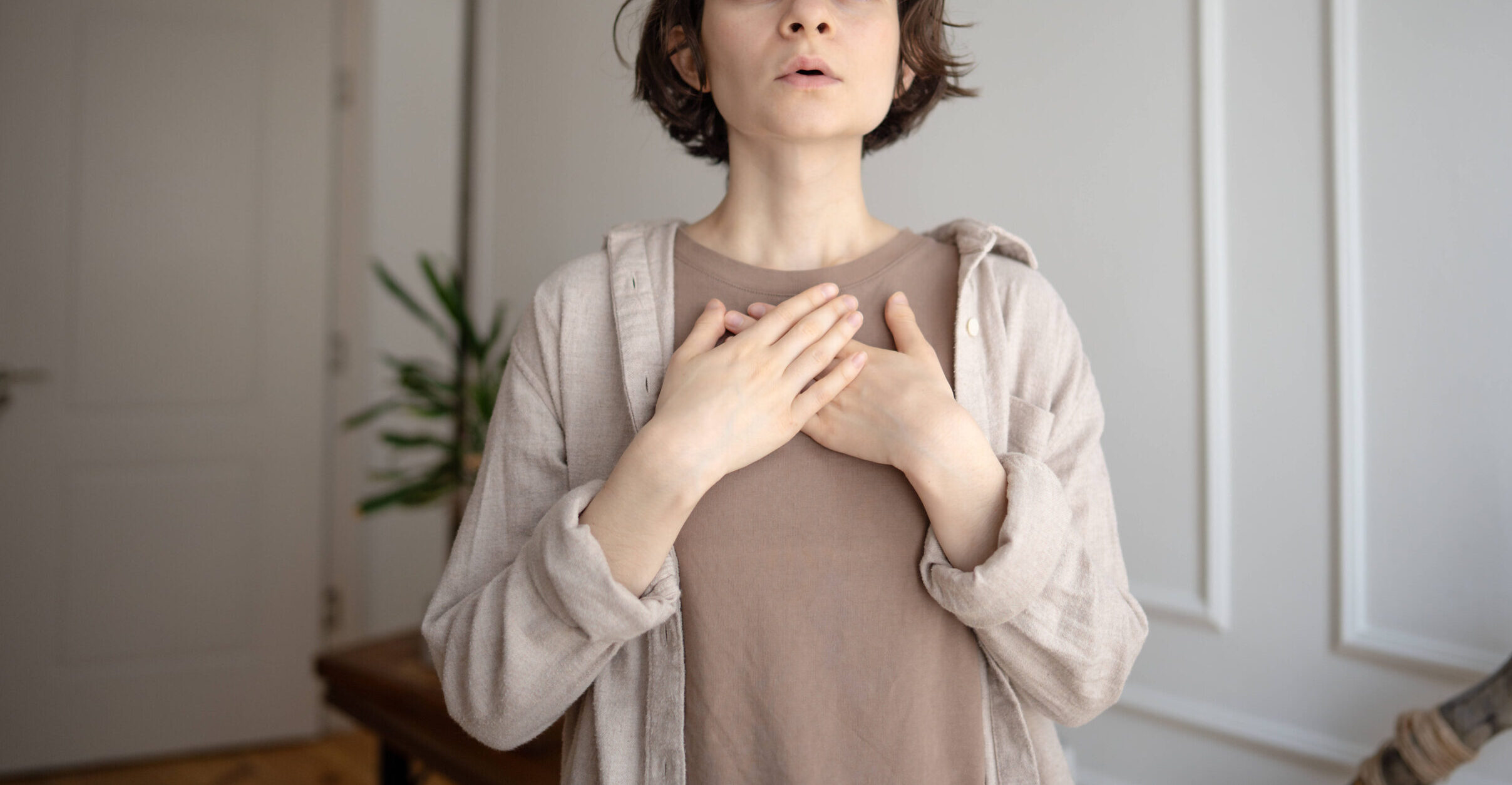 Junge Frau praktiziert Stressabbau, macht Atemübungen zur Beruhigung,