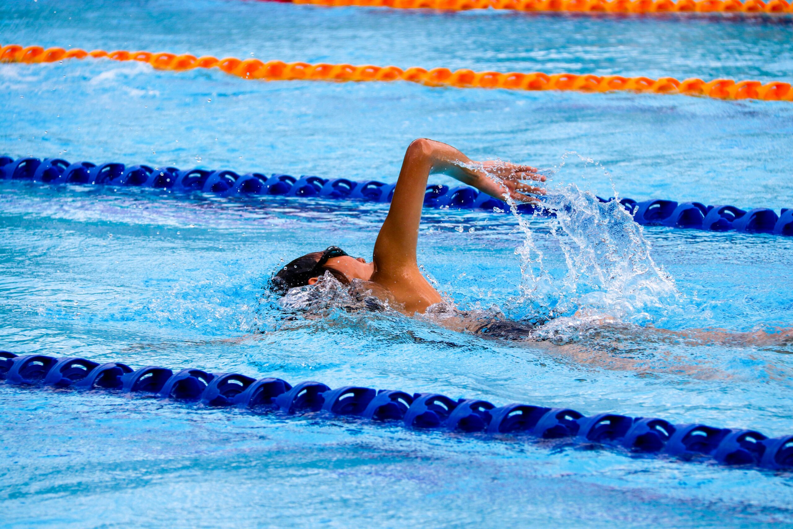 Mensch mit Kappe schwimmt im Schwimmbad