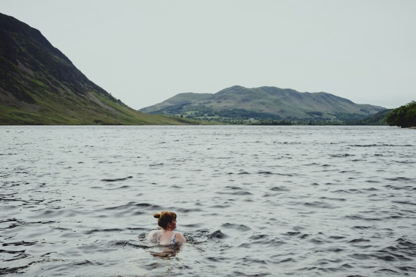 Frau schwimmt in einem See mit Bergen im Hintergrund