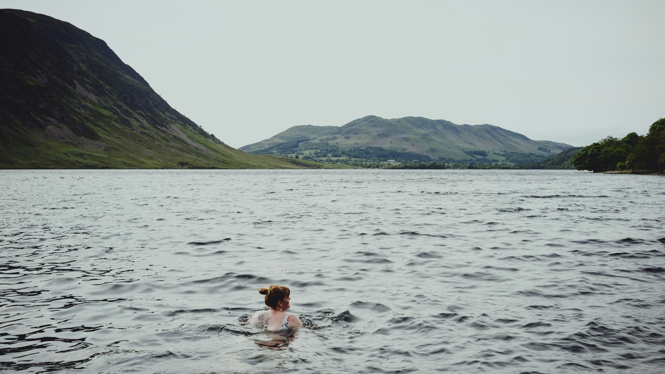 Frau schwimmt in einem See mit Bergen im Hintergrund