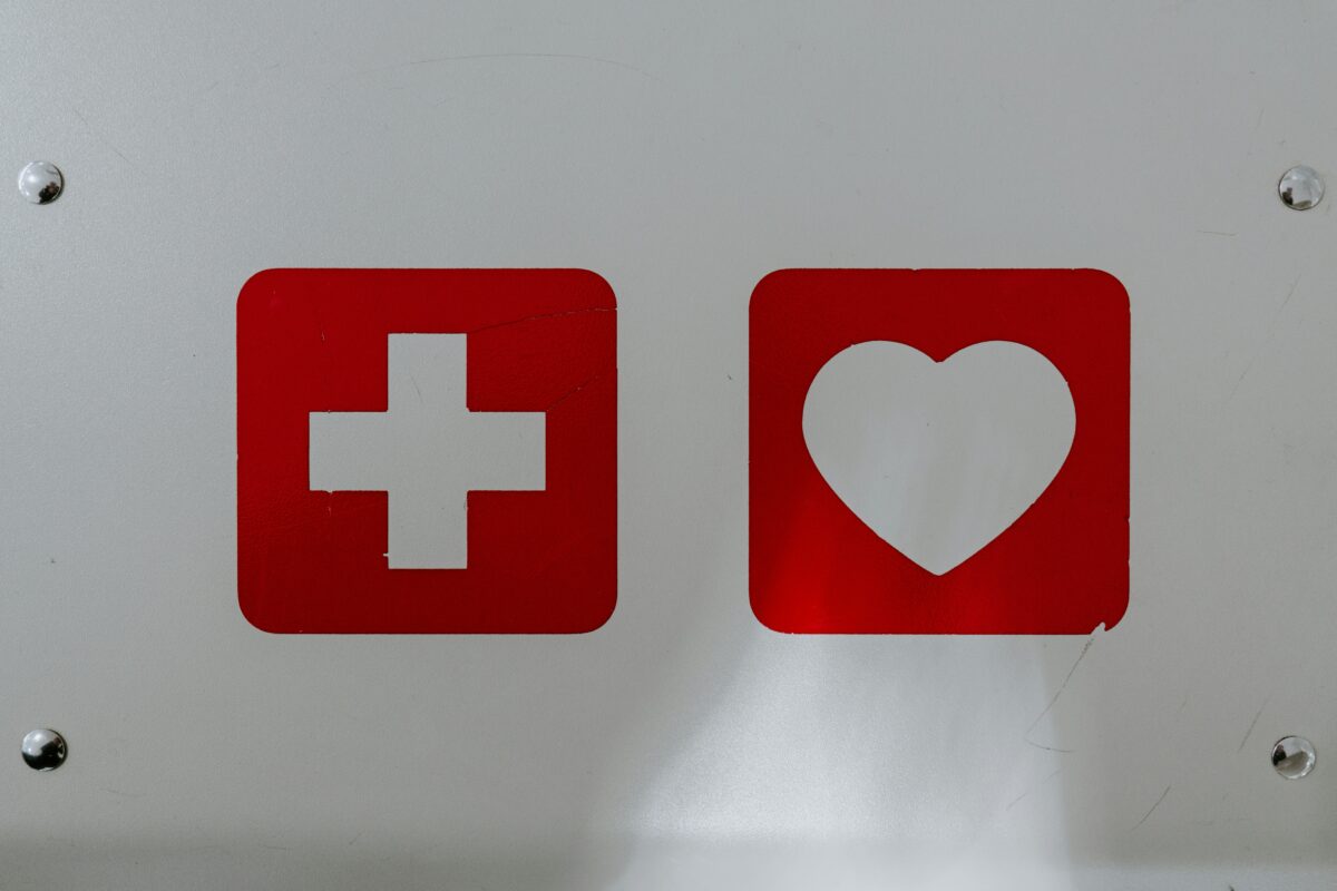 Herz- und Kreuz-Symbol an einer weißen Plakette
